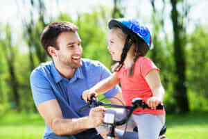 Child riding a bike with dad
