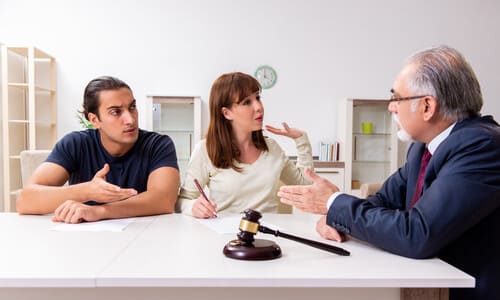 A young couple seated at a desk seeking legal advice from an old lawyer.