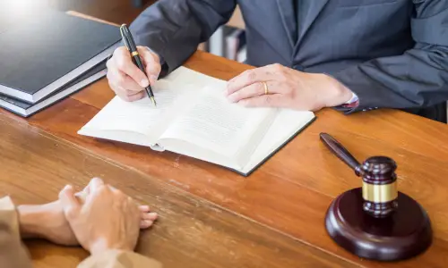 A deathbed will lawyer with law books and notebooks writing notes with his pen.