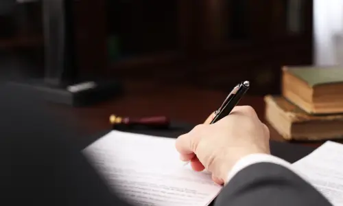 An over-the-shoulder shot of a joint will lawyer working on a document for a client.