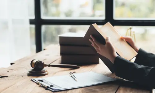 A QTIP trust lawyer holding a law book open while seated at a desk in her office.
